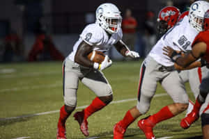 Football Player Running With Ball During Game Wallpaper