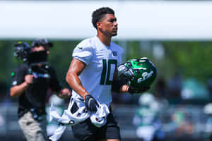 Football Player Walking With Helmet And Gear Wallpaper