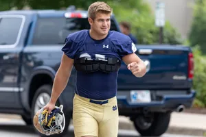 Football Player Walking With Helmetand Pads Wallpaper