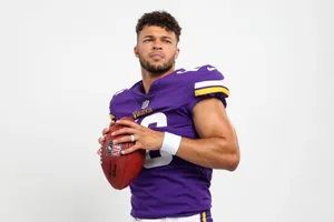 Football Playerin Purple Jersey Holding Ball Wallpaper