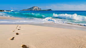 Footprints On A Beach With Waves And An Island Wallpaper