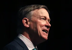 Former Governor, John Hickenlooper, Delivering A Speech Against A Black Backdrop. Wallpaper
