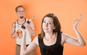 Frustrated Woman And A Man With Reciprocal Saw Against An Orange Background Wallpaper