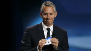 Gary Lineker, Eloquent Football Broadcaster, Delivering A Presentation On Stage. Wallpaper