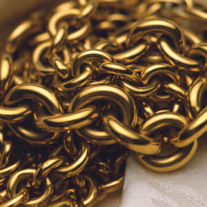 Gold Chain Necklaces On A White Cloth Wallpaper