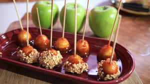 Gourmet Caramel Apples On A Rustic Wooden Table Wallpaper