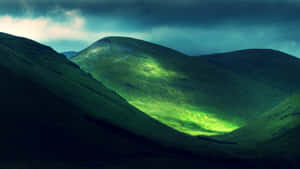 Green Hills Under Dark Clouds Wallpaper