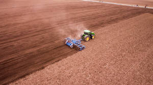 Groundbreaking Performance: John Deere Tractor In Vast Field Wallpaper