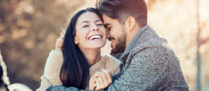 Happy Couple Embracing Outdoors Wallpaper