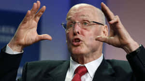 Henry Paulson Animatedly Gesturing During A Speech Wallpaper