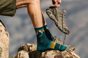 Hiker Putting On Shoe Outdoors Wallpaper