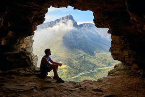 Hiker Sitting Alone Inside A Cave Wallpaper