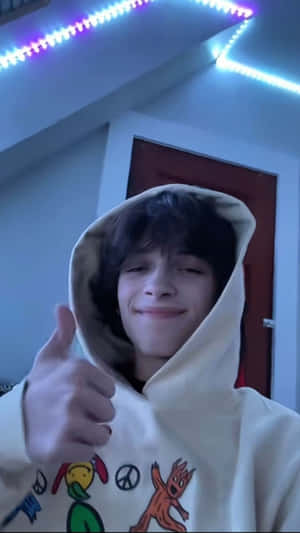 Hoodie Wearing Individual Giving Thumbs Up Wallpaper