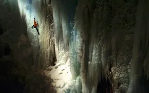 Ice Climber Conquers A Challenging Frozen Waterfall Wallpaper
