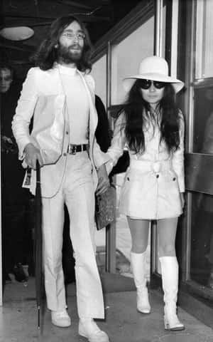 Iconic Photo Of Yoko Ono Walking Hand In Hand With John Lennon Wallpaper