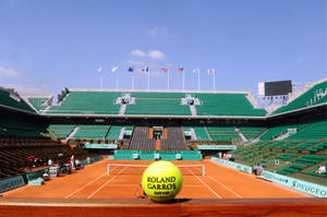 Intensity On Clay - A Close-up Of A Tennis Ball On French Open Court Wallpaper