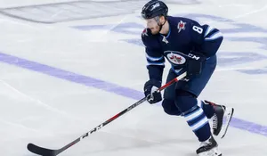 Jacob Trouba Gliding On Ice While Holding Hockey Stick In Front During Game Wallpaper