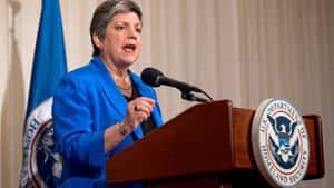 Janet Napolitano Speaking On Podium Wallpaper