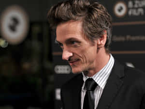 John Hawkes Striking A Pose In A Black Suit Wallpaper