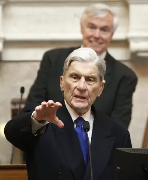 John Warner In Black Suit Raising His Hand Wallpaper