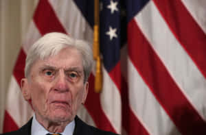 John Warner In Front Of Us Flag Wallpaper