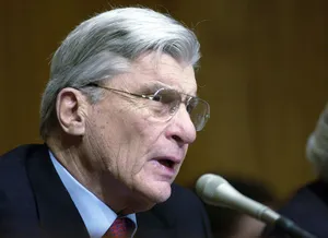 John Warner Speaking Into A Microphone Wallpaper