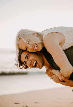 Joyful Beach Couple Piggyback Wallpaper