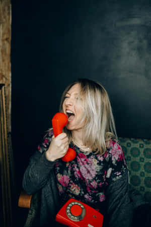 Joyful Woman Yelling Into Red Phone Wallpaper