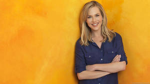 Julie Benz Cutely Posing On A Yellow Wall Wallpaper