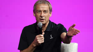 Jurgen Klinsmann Speaking On Microphone Wallpaper