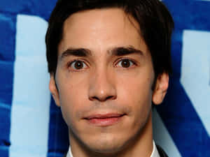 Justin Long Smiling On A Red Background Wallpaper