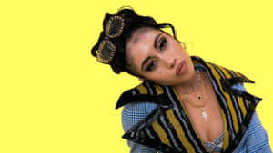 Kali Uchis Yellow Backdrop Stylish Pose Wallpaper