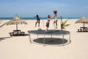 Kids Jumping On A Trampoline Near The Beach Wallpaper