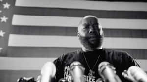 Killer Mike Speakingat Podium Wallpaper