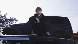 Lee Know Sittingon Car Hood Wallpaper