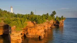 Lighthouse Overlooking Cliffside Waters Wallpaper