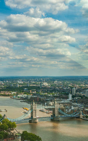 London's Iconic Tower Bridge Underneath A Cloudy Sky Wallpaper