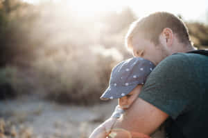 Lovely Photo Of A Father Hugging His Tangible Baby Under The Sunlight Wallpaper