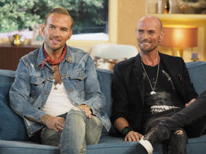 Luke Goss And Matt Goss On A Blue Couch Wallpaper