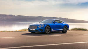 Luxurious Bentley Continental Gt Cruising Down The Road Wallpaper