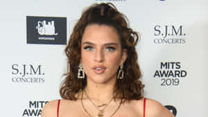 Mae Muller Poses Confidently During A Photoshoot. Wallpaper