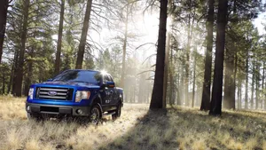 Majestic Blue Ford F-150 Pickup Truck In Untamed Forest Wallpaper