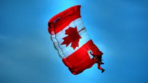 Majestic Shot Of Canada Flag Floating On A Parachute Against The Blue Sky Wallpaper
