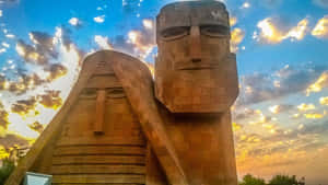 Majestic View Of We Are Our Mountains Monument Against A Vibrant Sunset Wallpaper