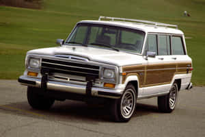 Majestic Vintage Jeep Wagoneer Cruising On A Scenic Road Wallpaper