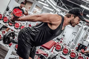 Man Exercising Dumbbell Row Gym Setting Wallpaper