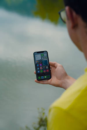 Man Holding A Black Iphone Ios 12 Wallpaper