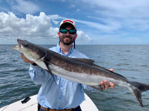 Man Holding Cobia Fishat Sea Wallpaper