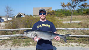 Man Holding Large Fish Outdoors Wallpaper