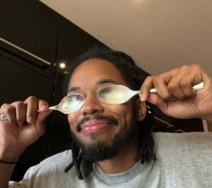 Man Holding Spoons Over Eyes Wallpaper